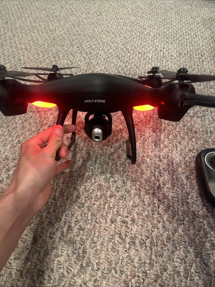 Holy Stone HS100 GPS drone with red LEDs and front camera/gimbal, held in hand