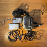 Silver compact digital camera with gray pouch case, charger and cables