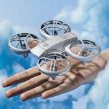 Silver mini FPV drone with four propeller guards, held in a hand