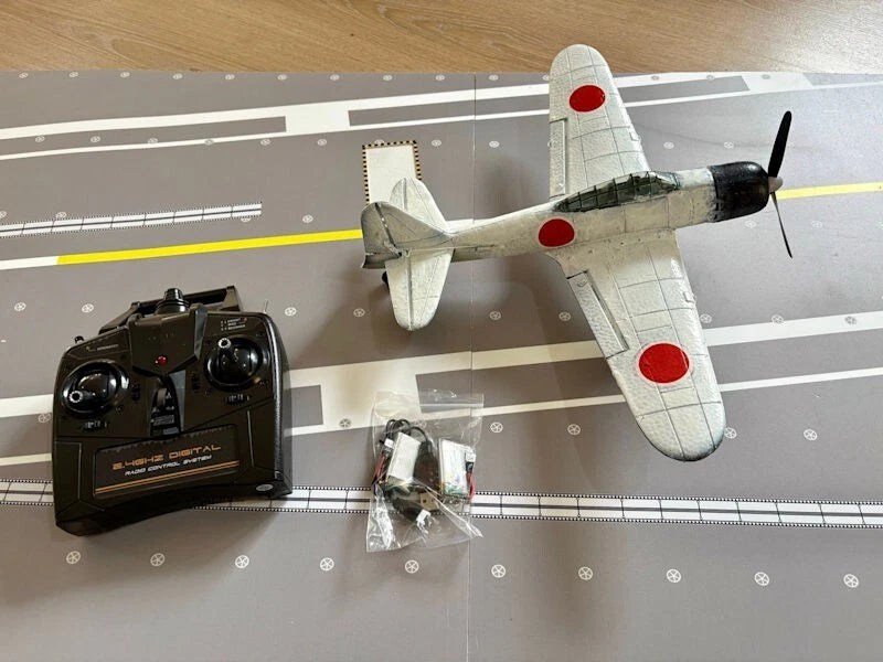 White RC warbird model with red roundels and propeller, mounted on stand