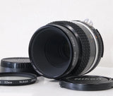 Black Nikon Micro-Nikkor 55mm f/2.8 macro SLR lens with front glass and caps