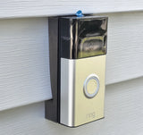 Silver battery doorbell with circular button, mounted on vinyl siding