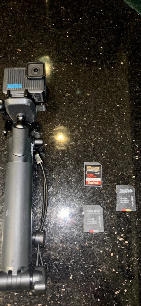 Gray action camera on detachable tripod with SD memory cards