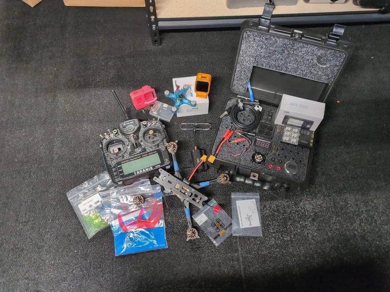 FPV drone toolkit bundle with parts, cables, and charger in a storage case