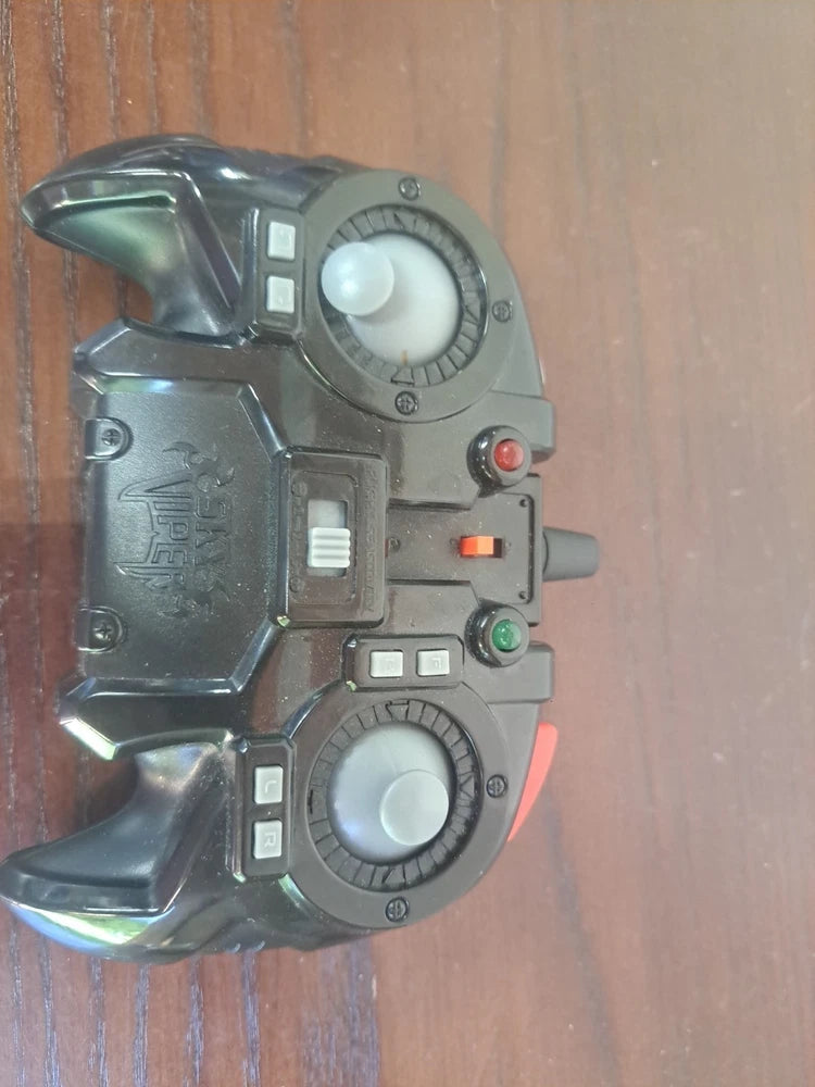 Grey drone remote controller with large thumb dial, buttons, and trigger.