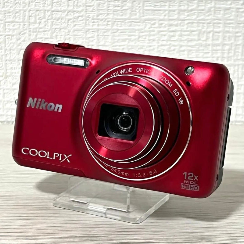 Red Nikon COOLPIX compact digital camera with front lens and 12x zoom ring