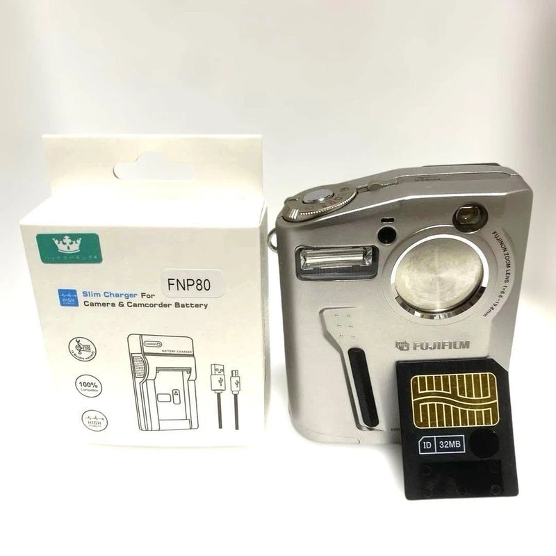 Silver compact digital camera with lens, flash, and visible memory card