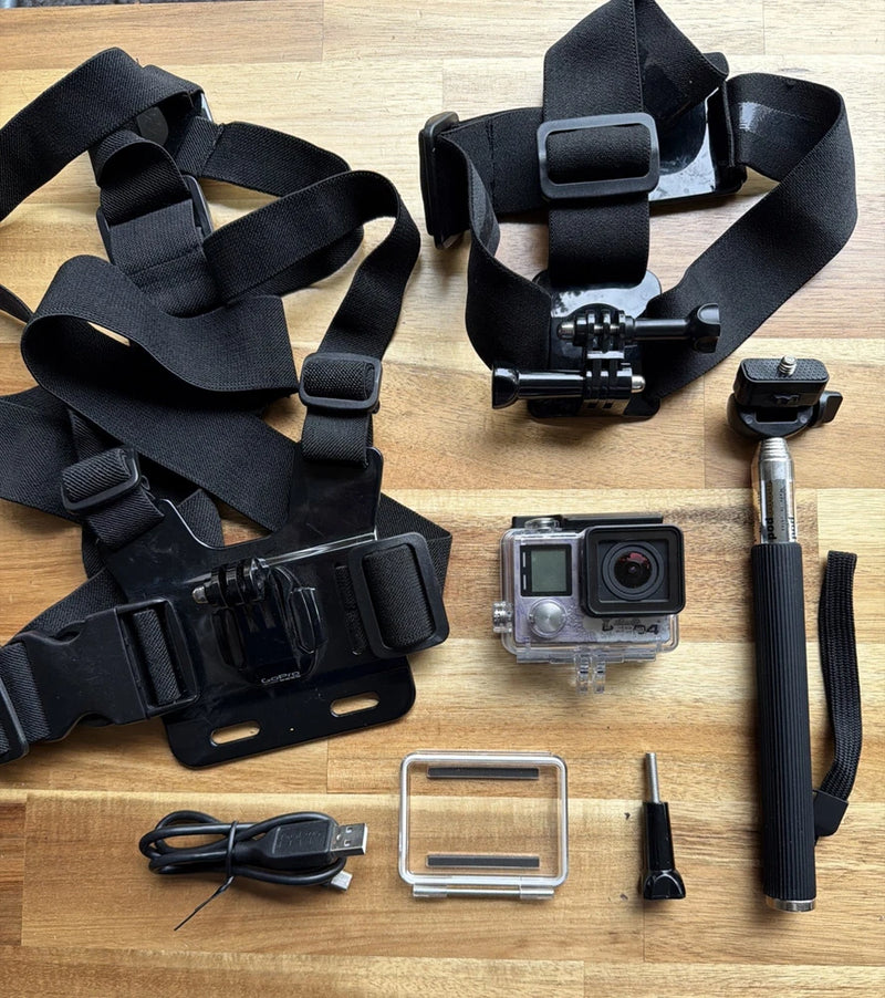 Black action camera with waterproof housing, head strap, mounts and charging cable, accessories