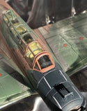 Die-cast model airplane with green wings and dark navy fuselage, open cockpit canopy