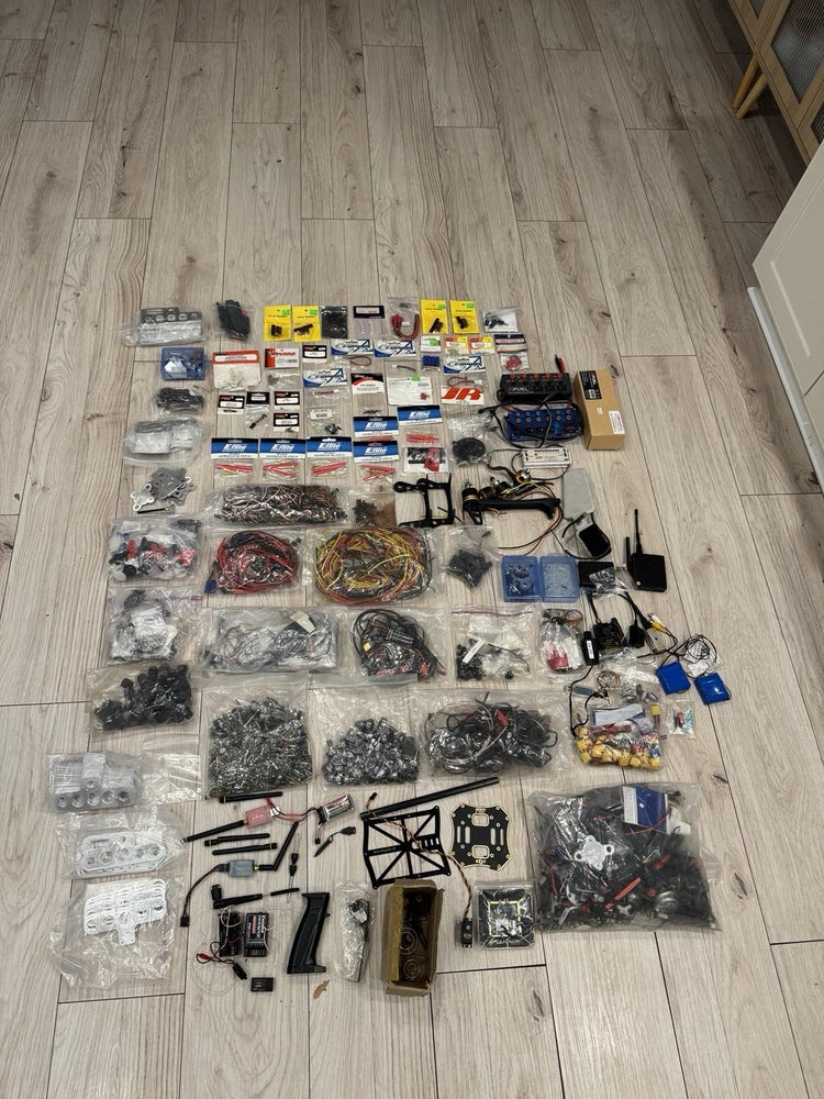 Drone builder parts lot with motors, ESCs, frames, and wiring accessories in sealed bags