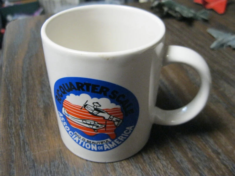 White coffee mug with blue airplane logo on front and right-side handle.