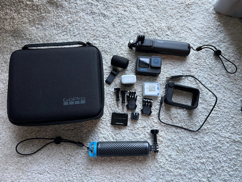 Black action camera kit with carrying case, mounts, handheld grip, battery, and cables