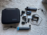 Black action camera kit with carrying case, mounts, handheld grip, battery, and cables