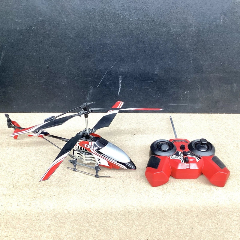 RC helicopter with red and white skids and blades, beside black and red radio controller