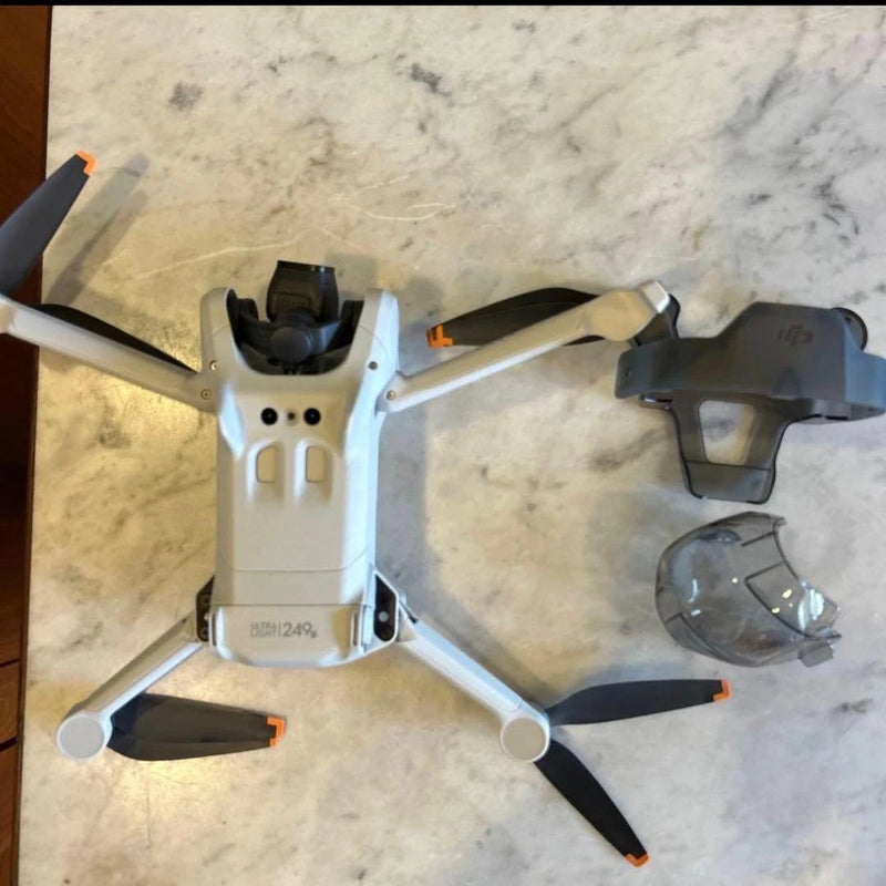 DJI Mini 3 drone with RC controller, white foldable arms and propellers.
