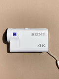 Silver Sony action cam with 4K label and Zeiss branding, side view with lens housing