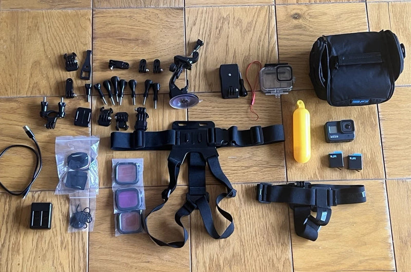 Black action camera bundle with waterproof housing, mounts, straps, battery, and case