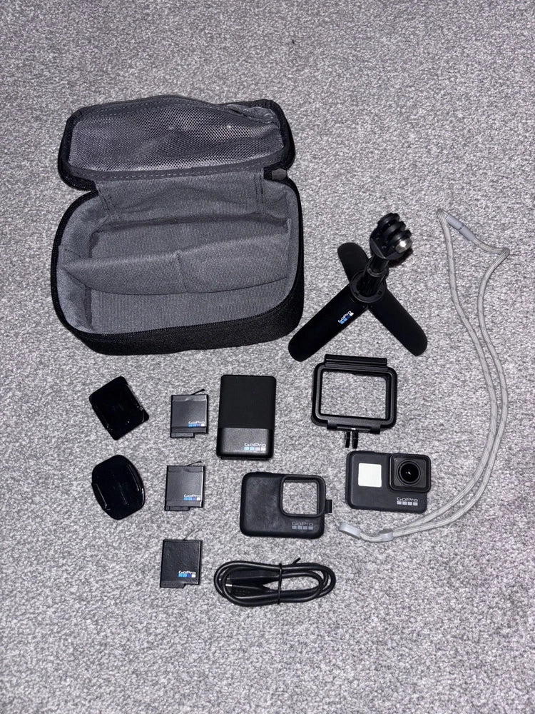 Black action camera with frame, mounts, batteries, cables, and soft case
