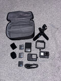 Black action camera with frame, mounts, batteries, cables, and soft case