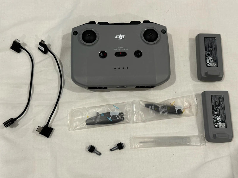 Drone remote controller with DJI branding, two batteries, cables, and accessories
