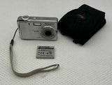 Silver digital camera with lens, wrist strap, battery, and black soft case pouch
