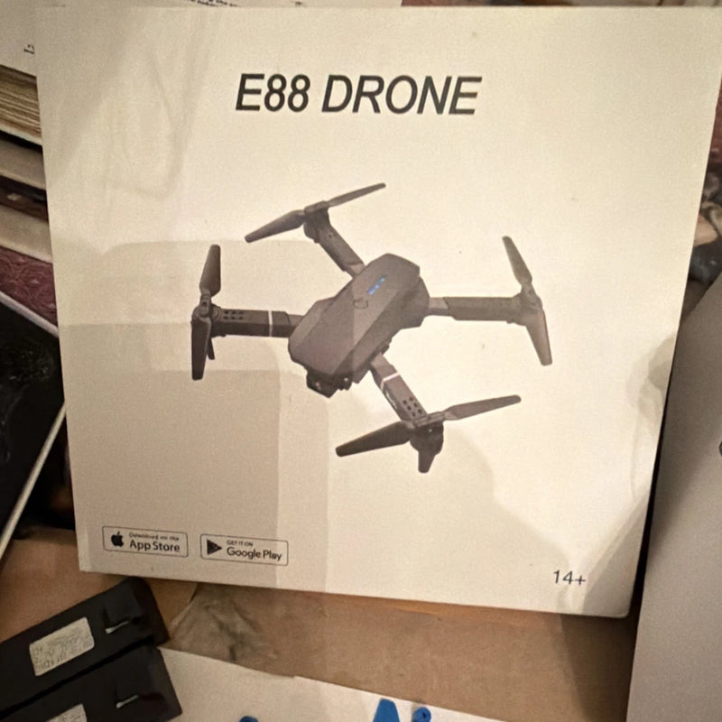 Black foldable quadcopter drone shown on retail box packaging