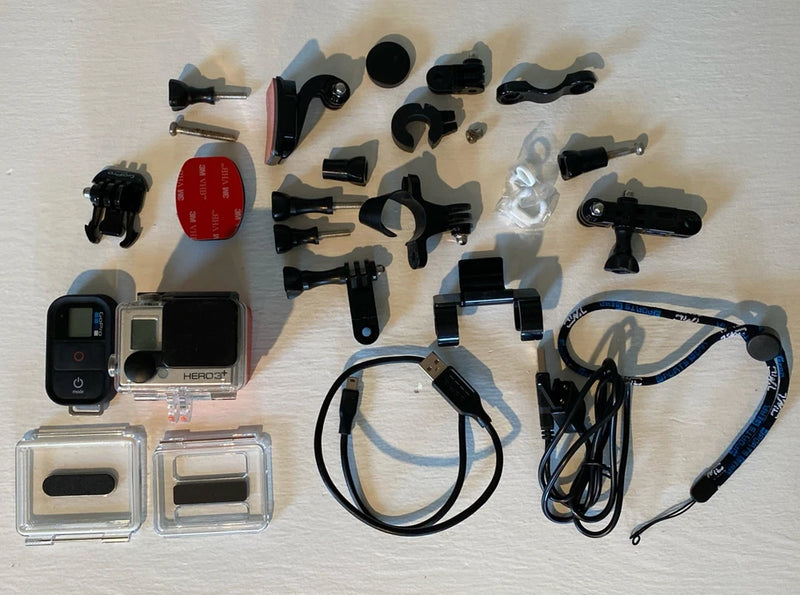 Silver action camera with housing and multiple mounts, clips, and cables accessories kit