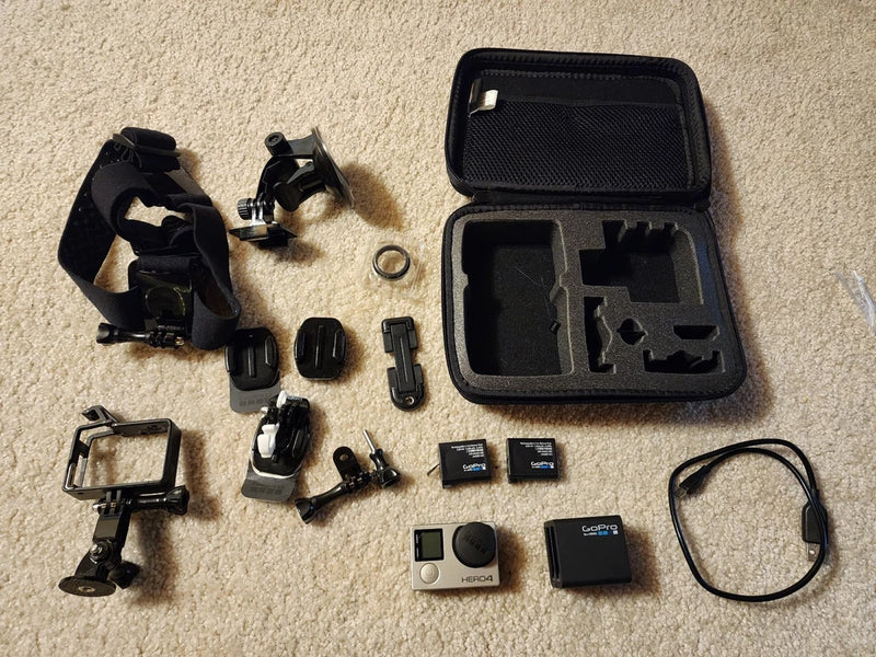 Action camera accessory kit in black case with mounts, batteries, cables, and charger