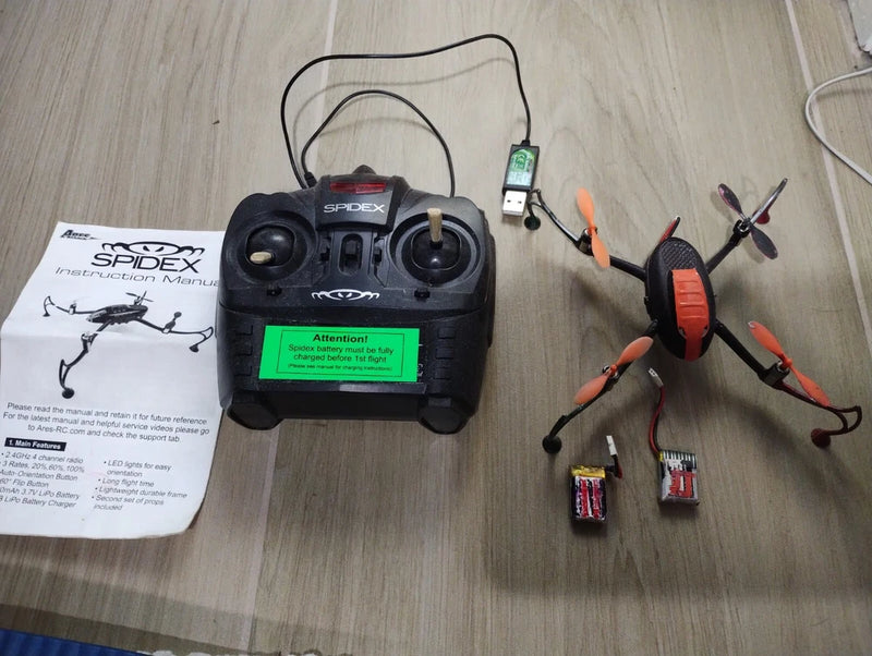 Black drone remote controller with screen and quadcopter frame, orange propeller arms