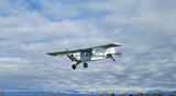 White and green high-wing RC airplane with landing gear and propeller, in flight