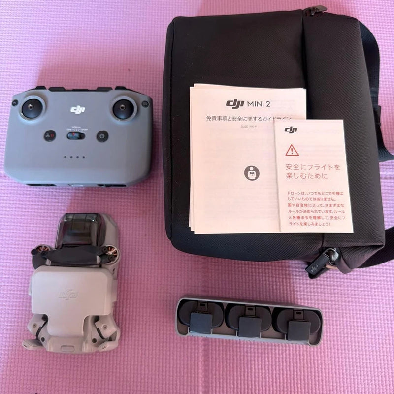 Compact camera drone kit with gray drone body, case, and spare battery holders