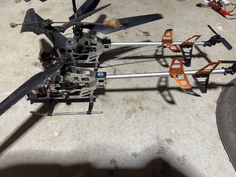 Dual-blade RC helicopter frame with orange landing skids and two rotor blades