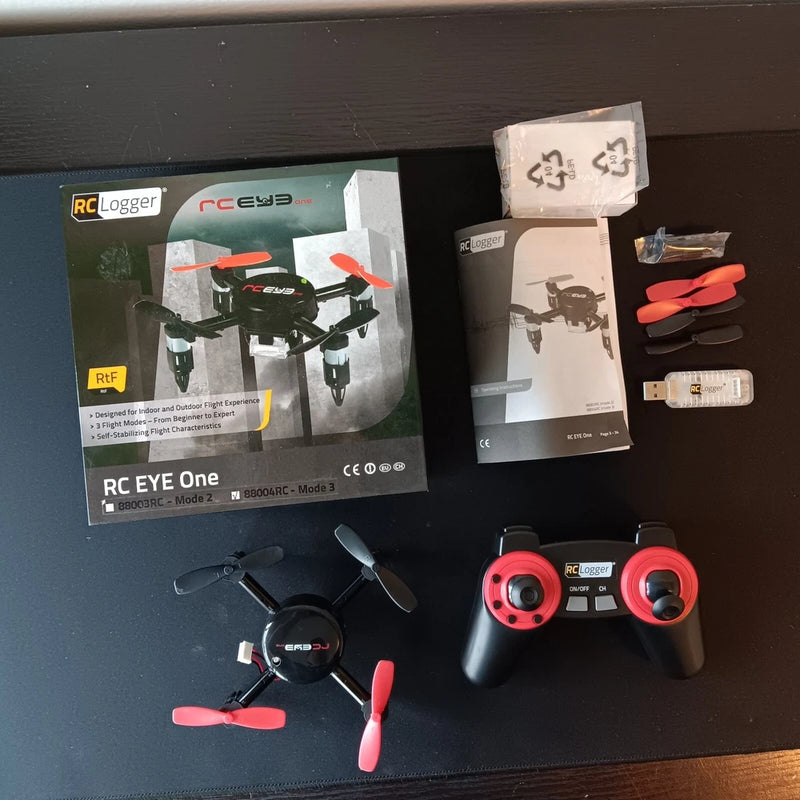 RC quadcopter drone kit with red-and-black controller, propellers, and battery