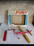 Vintage battery-powered flying model airplane, red and yellow with launcher tube and box