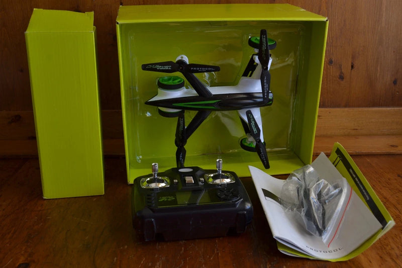 Green boxed RC flying car drone with quadcopter, remote controller, extra blades