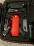 DJI drone with red body, folding arms, and accessory modules in hard case