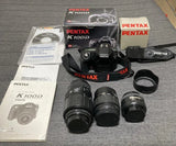 PENTAX K100D DSLR camera kit with three lenses, camera body, strap, and manuals