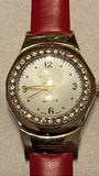 Vintage women's wrist watch with gold-tone case, rhinestone bezel, cream dial, burgundy strap