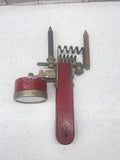 Vintage handheld battery tester with red handle and brass probe tips