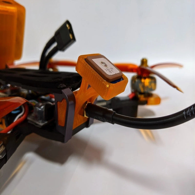 Orange 3D-printed GPS mount bracket with attached cable for FPV drone