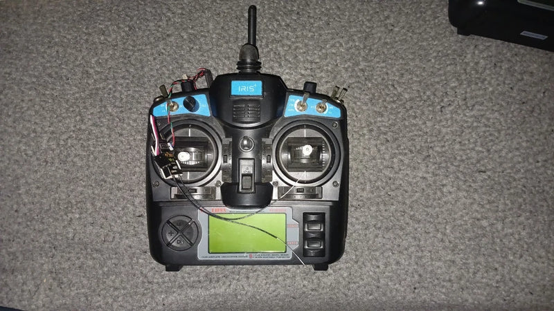 Black remote control transmitter with blue accents, LCD screen, and dual antennas