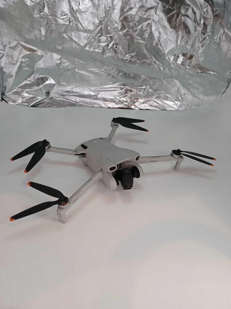 Compact quadcopter drone with four propellers, light gray body