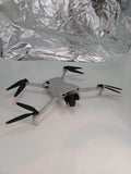 Compact quadcopter drone with four propellers, light gray body