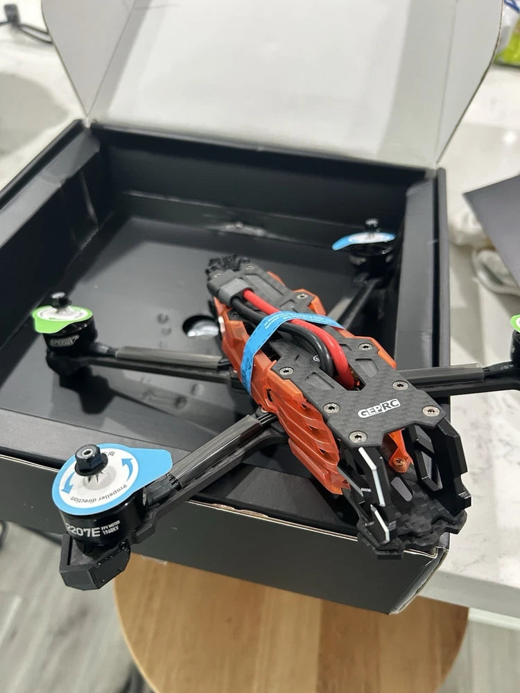 Orange and gray FPV drone frame with motor mounts and carbon arms