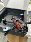 Orange and gray FPV drone frame with motor mounts and carbon arms