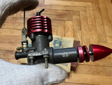 Model diesel RC airplane engine with red finned cylinder and black crankcase