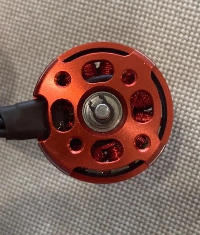 Red mini drone motor with circular housing, mounting holes, and exposed copper windings