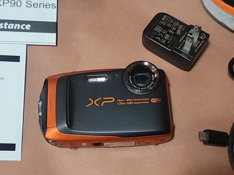 Orange and black waterproof digital camera with front lens and XP90 branding