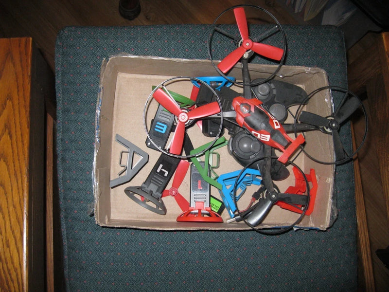 Assorted drone parts lot in open box, red and black frames with propellers