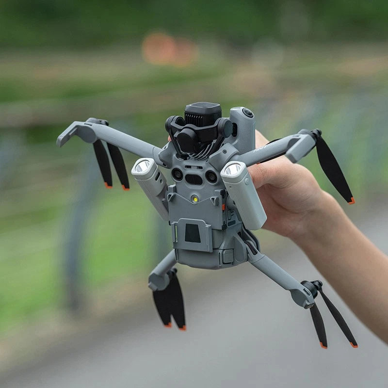 Drone with attached searchlight module and stabilizer arms, held in hand